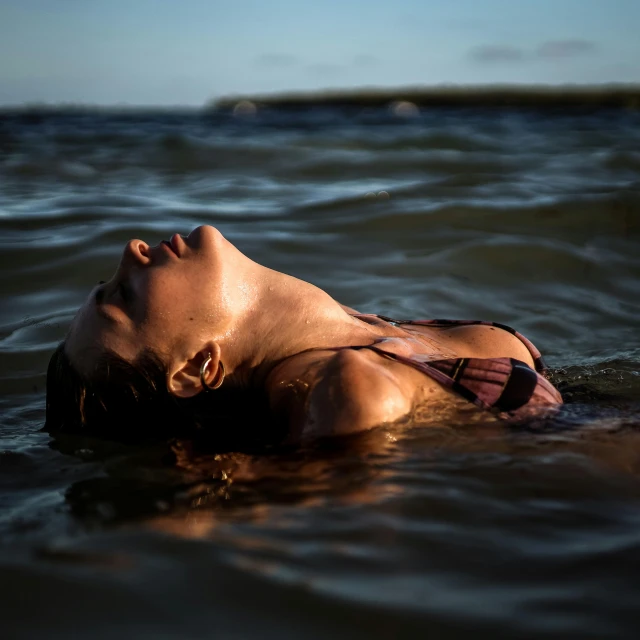 the woman is floating in the water near the shoreline