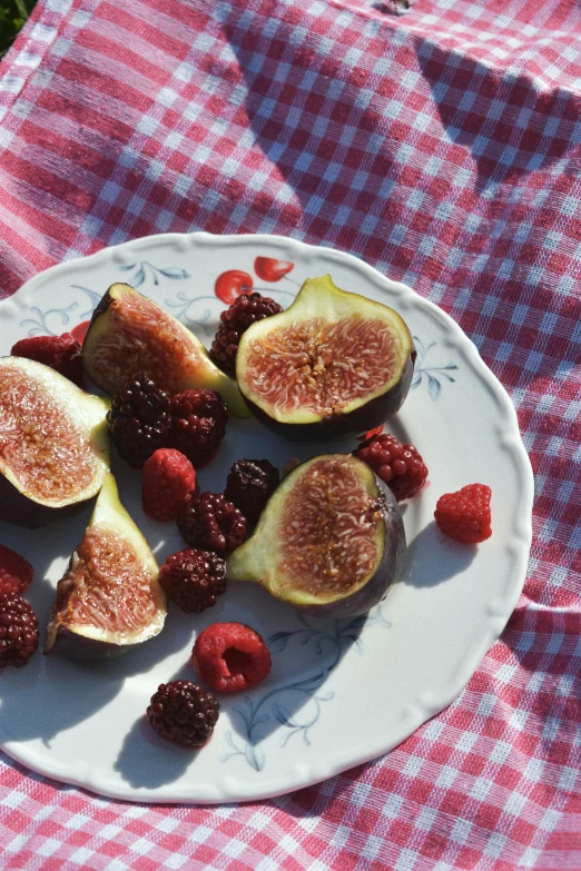 fresh fruit is on a plate on the picnic cloth