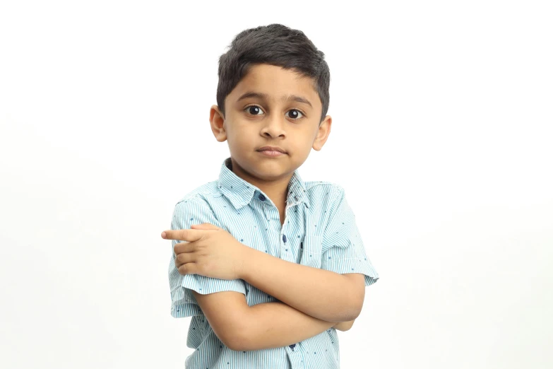 a boy looks into the camera while leaning his elbow against a white background