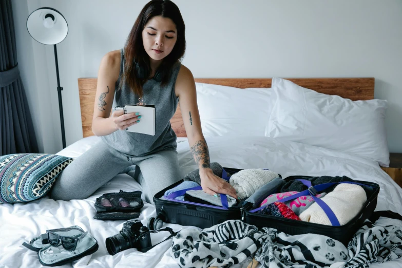 a woman sitting on a bed with her luggage open