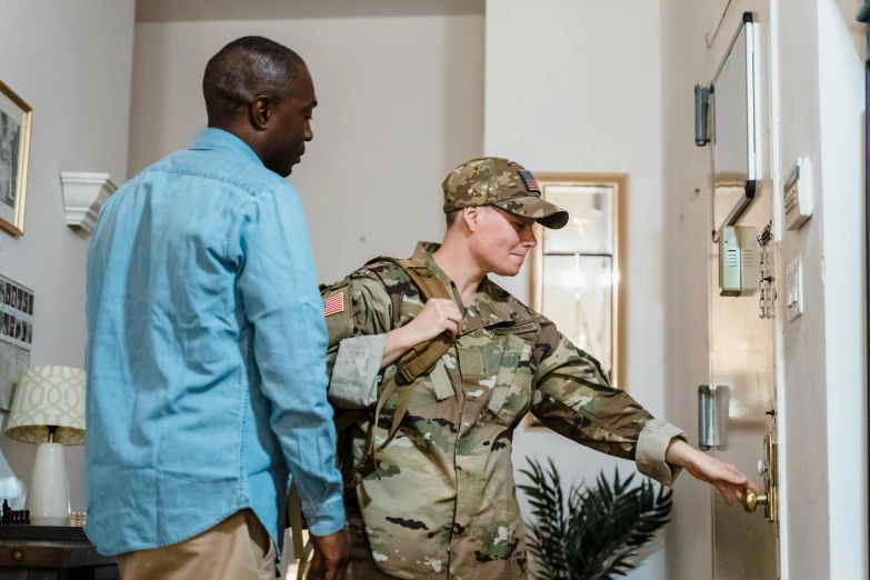 soldier in uniform is looking at another person who's about to reach the door