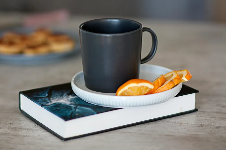 there are some oranges sitting on the plate with a cup