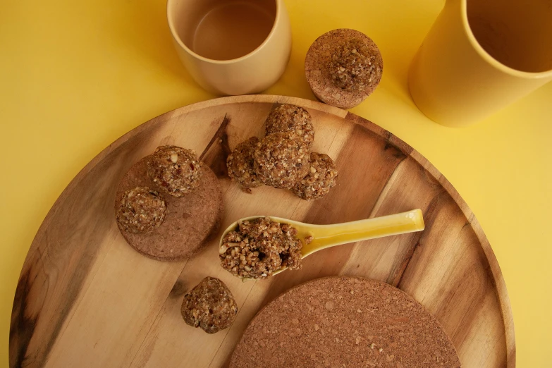 a wooden plate with some peanut er cookies next to a brown bowl