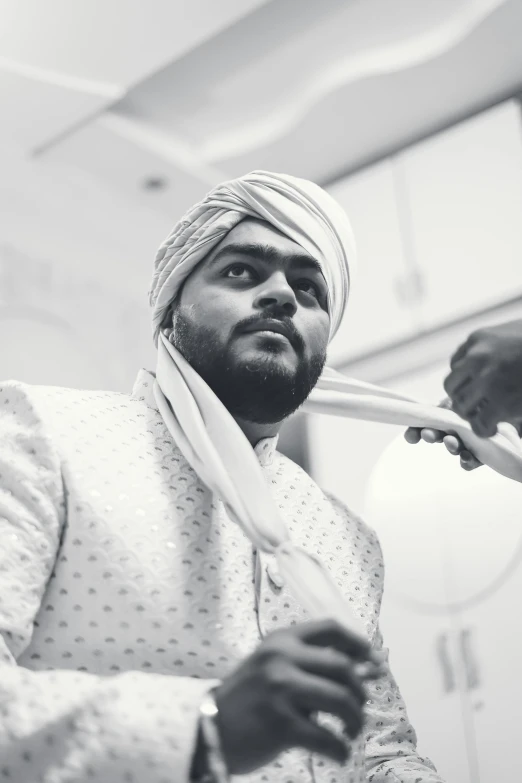 a person with an indian turban fixing his tie