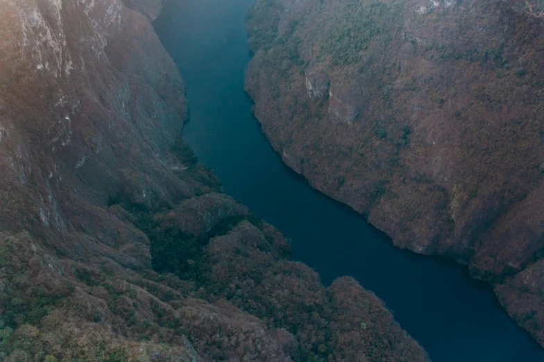 the view out an airplane window shows a river flowing between some mountains