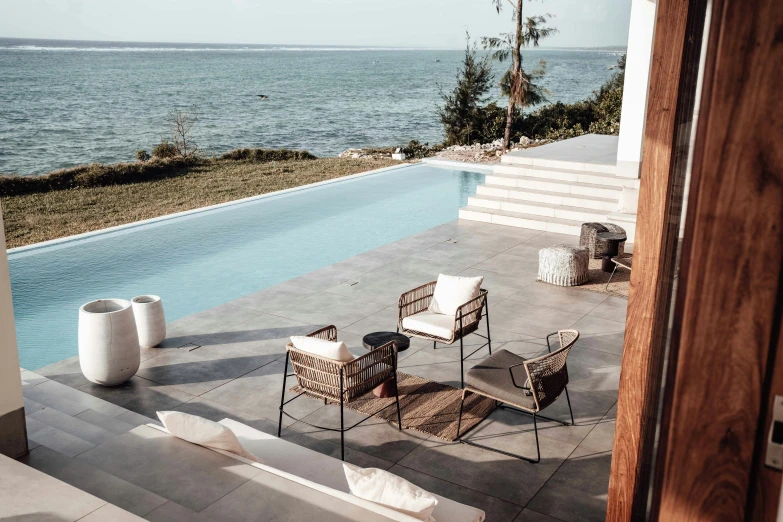 a patio area with chairs and table next to the water