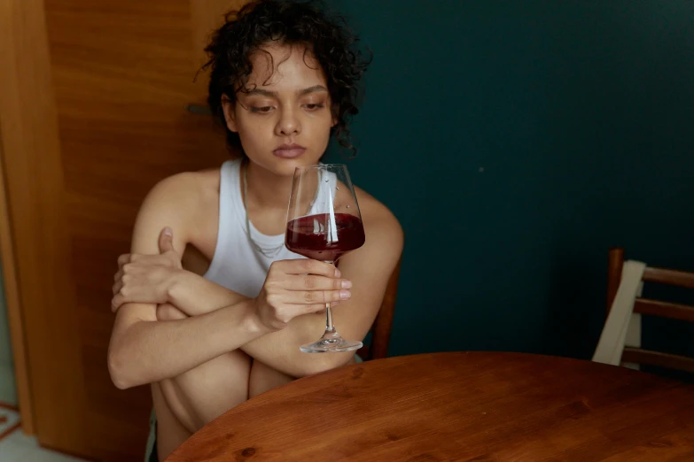 a woman is holding a glass of red wine