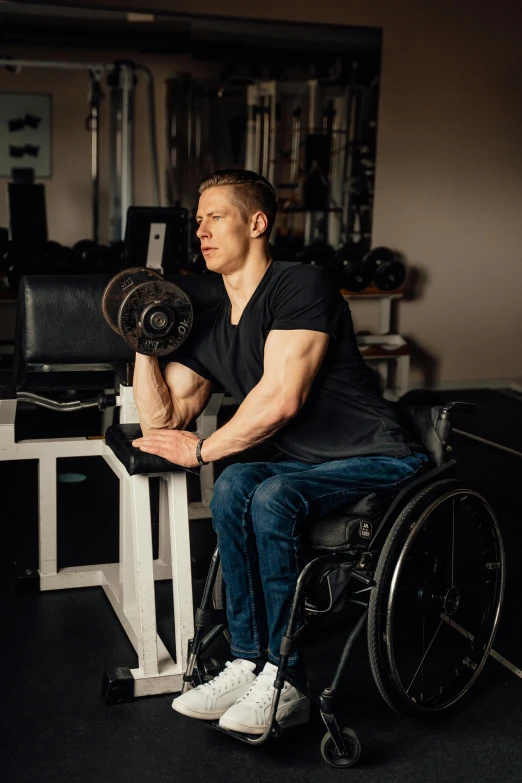 the man is in his wheelchair working on his arm muscles