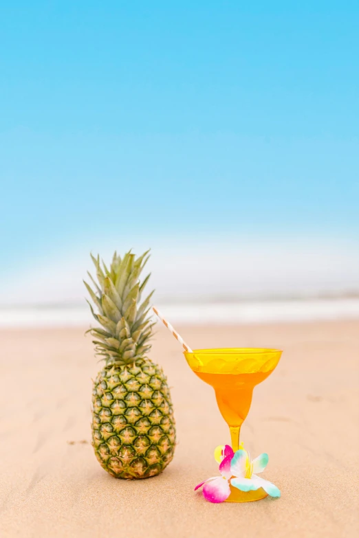 a pineapple drink and a cocktail glass on a beach