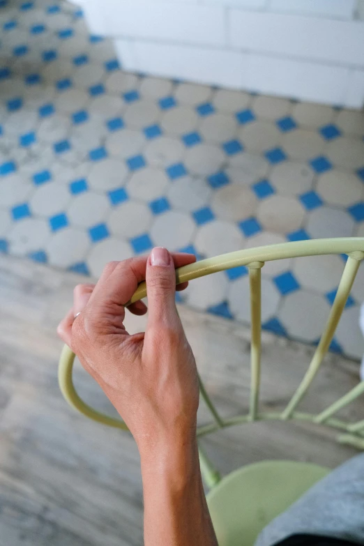 a hand holding the handle of a green chair