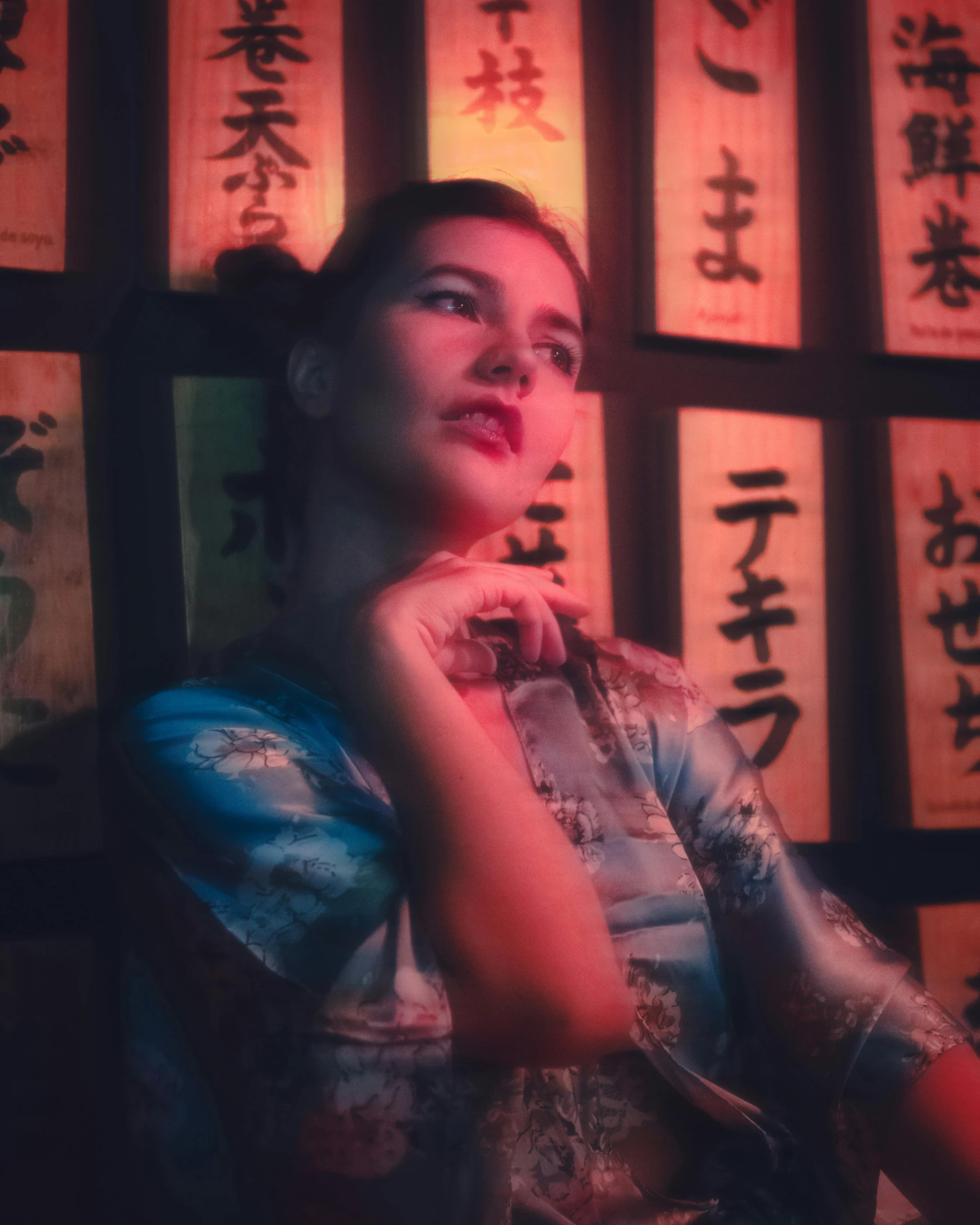 a woman stands against a wall full of asian calligraphy