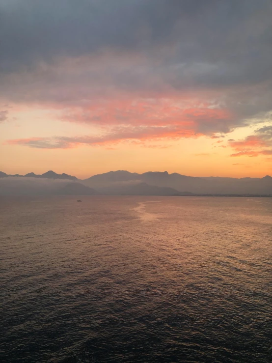 a calm lake under dark clouds as the sun sets