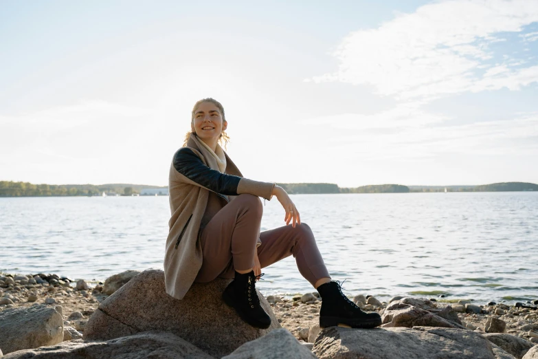 a woman in brown is sitting on a rock