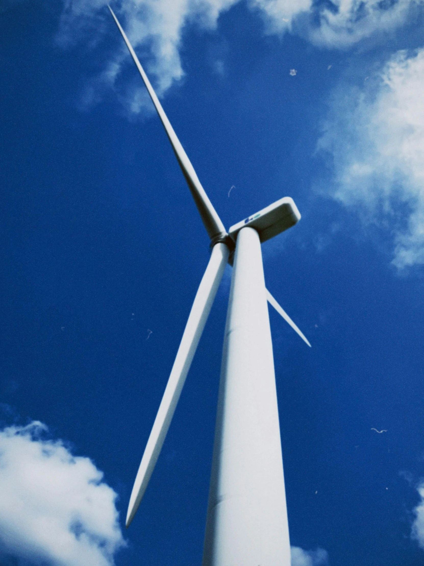 a white wind turbine against a partly cloudy blue sky