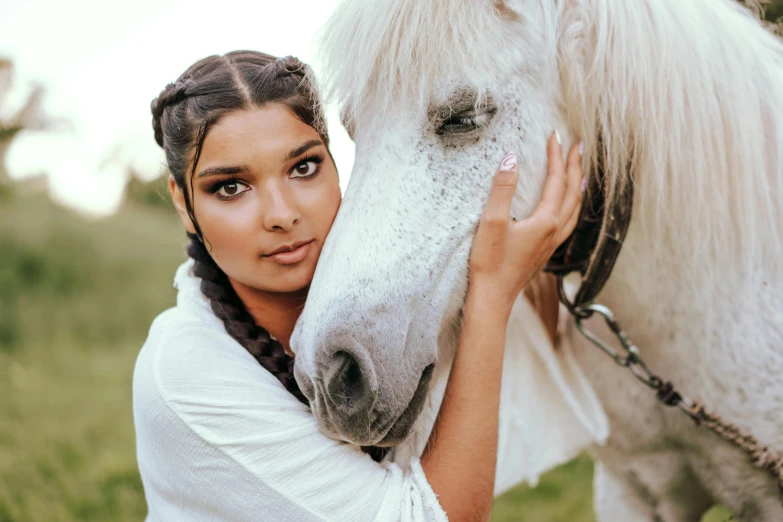 a beautiful woman standing next to a white horse