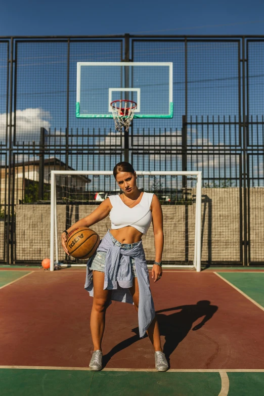 a woman holding a basketball and posing with a basket