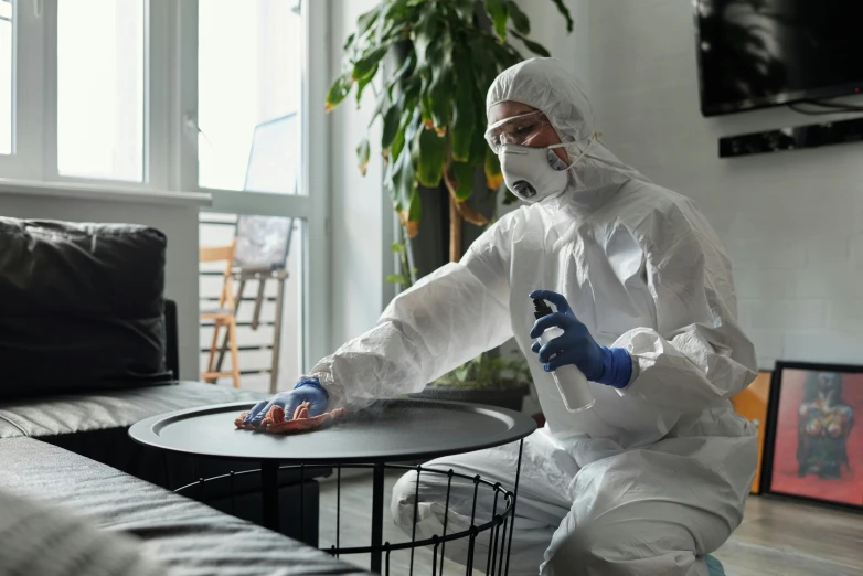 a person in white safety suit standing over a black table