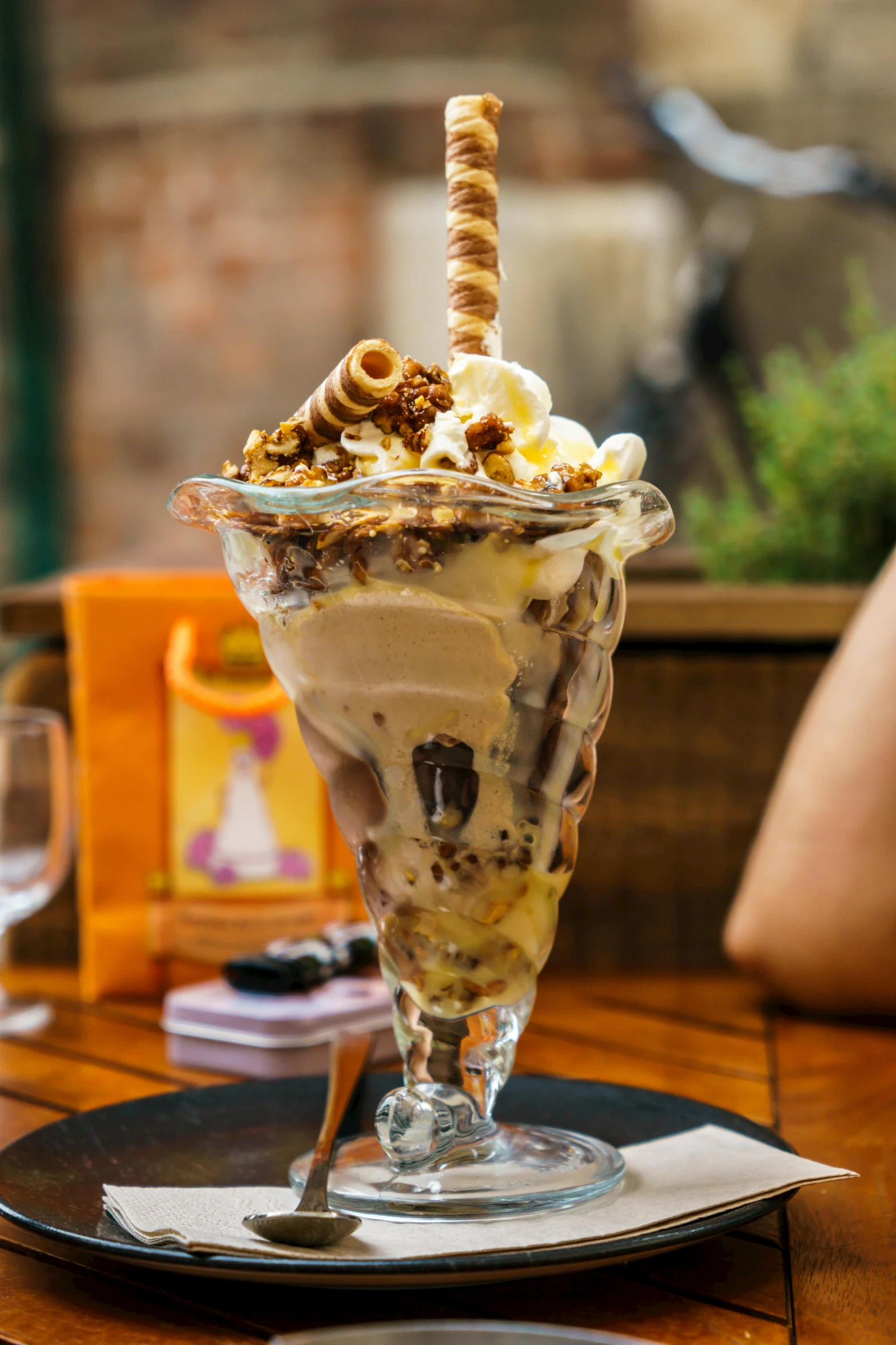 a dessert ice cream sundae on a table with a woman sitting in the back