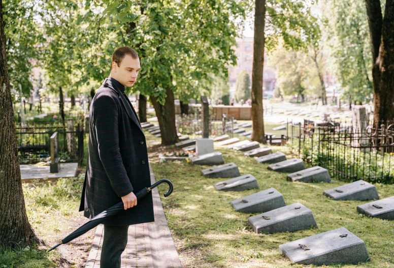 the man is standing in a cemetery with a large sword