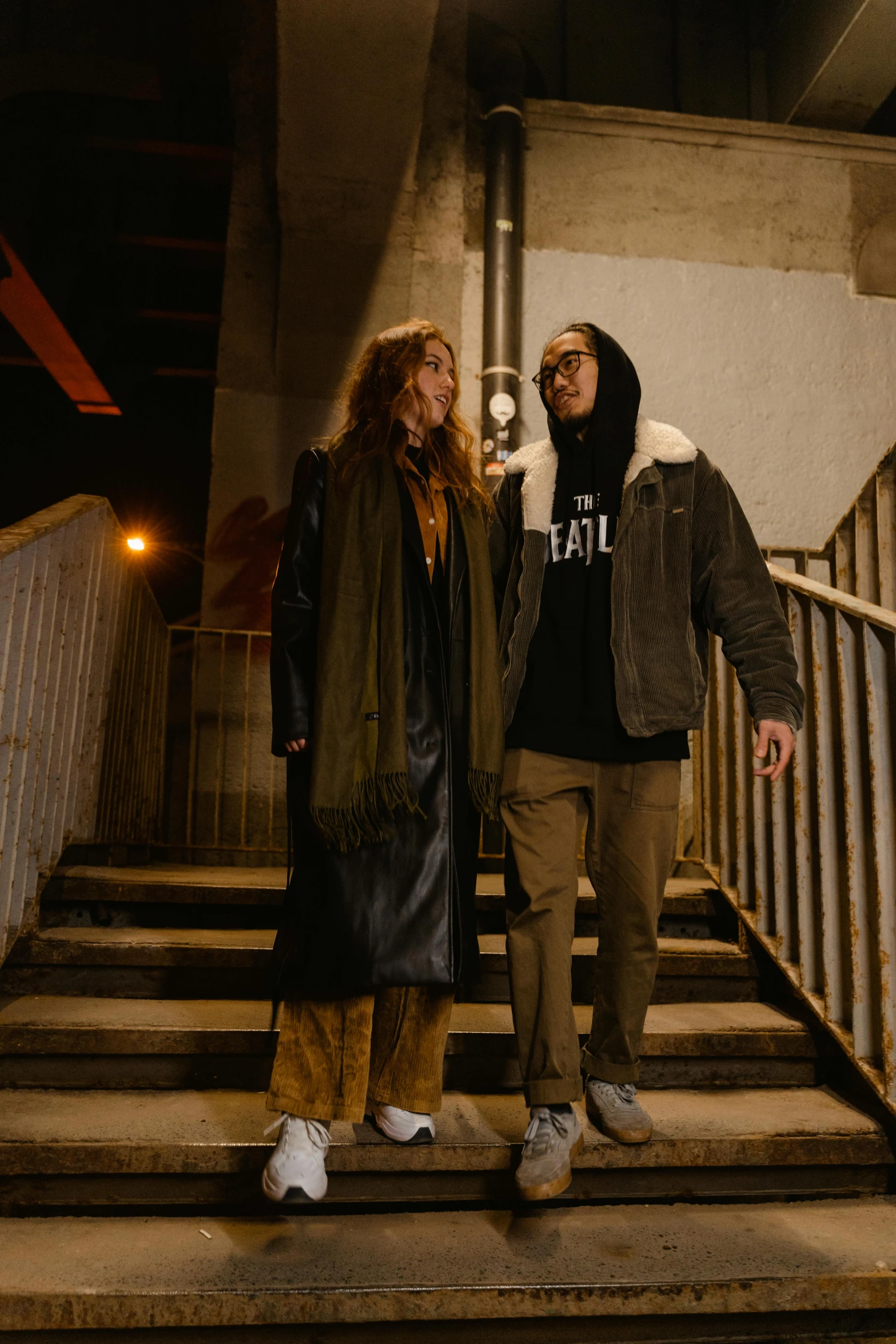 two people standing on steps next to a staircase