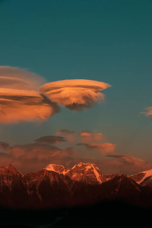 the clouds are lit up over the mountains