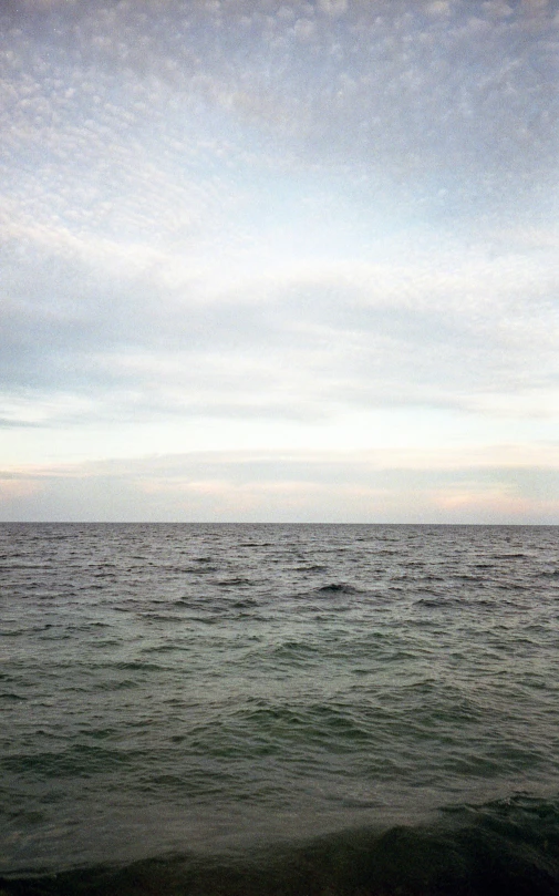 an ocean horizon with the water under cloudy skies