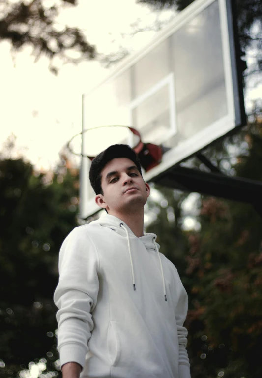 a man standing in front of a basketball hoop looking up