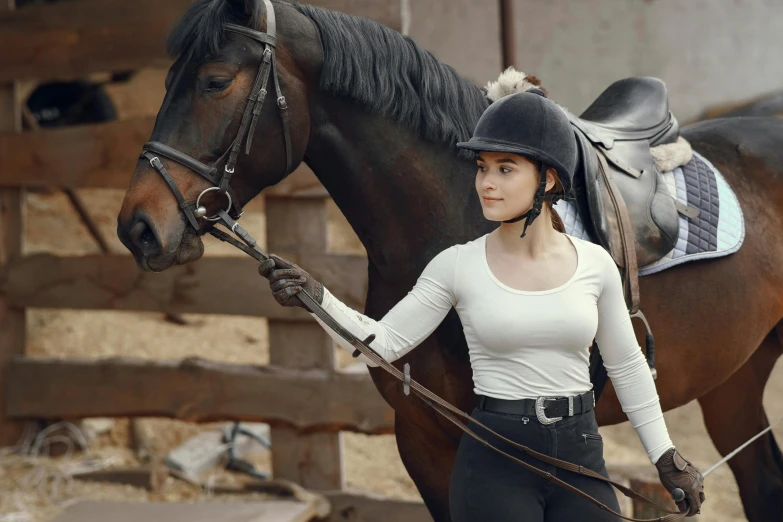 the woman is holding her reins by a brown horse