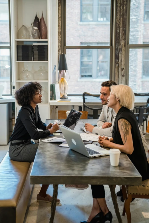 a woman working on a computer at a desk with others