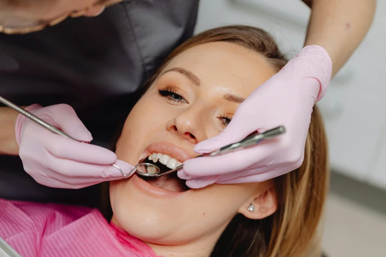 a woman has her teeth checked and the dentist is using tongs