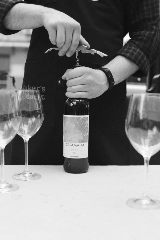 a person is plucking a bottle in front of three wine glasses