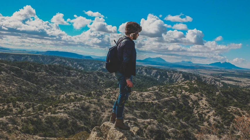 a person with a back pack standing on a rocky ledge