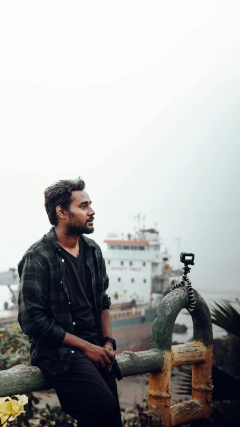 a man sits on a fence and looks ahead