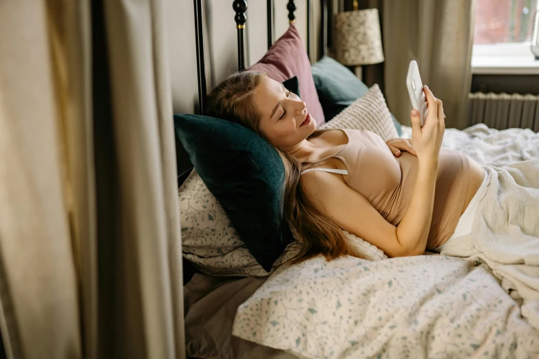 a girl laying on her bed holding onto her phone