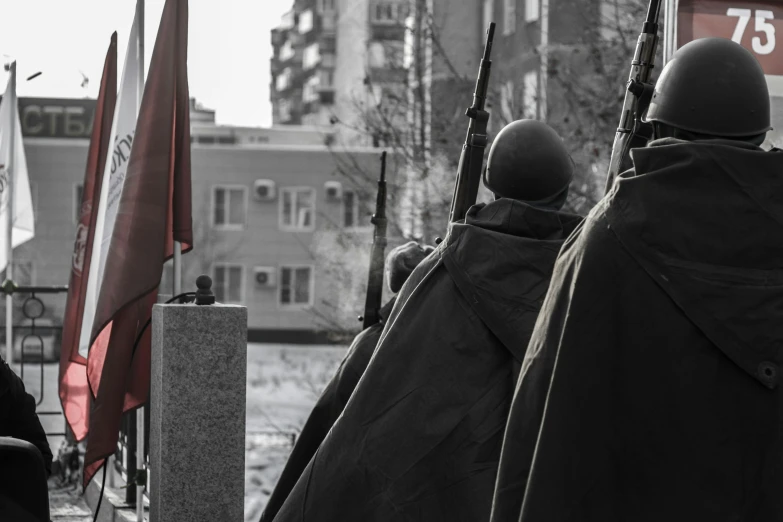 men in black coats with rifles standing by a building