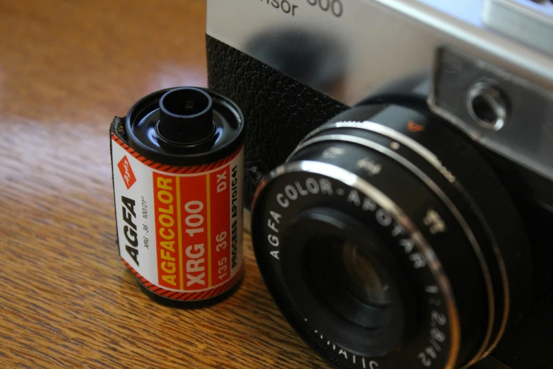 a can of soda and a camera on a wooden table