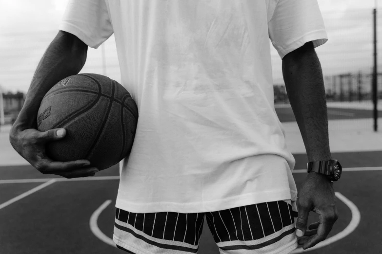 man in shorts holding up a basketball on a court