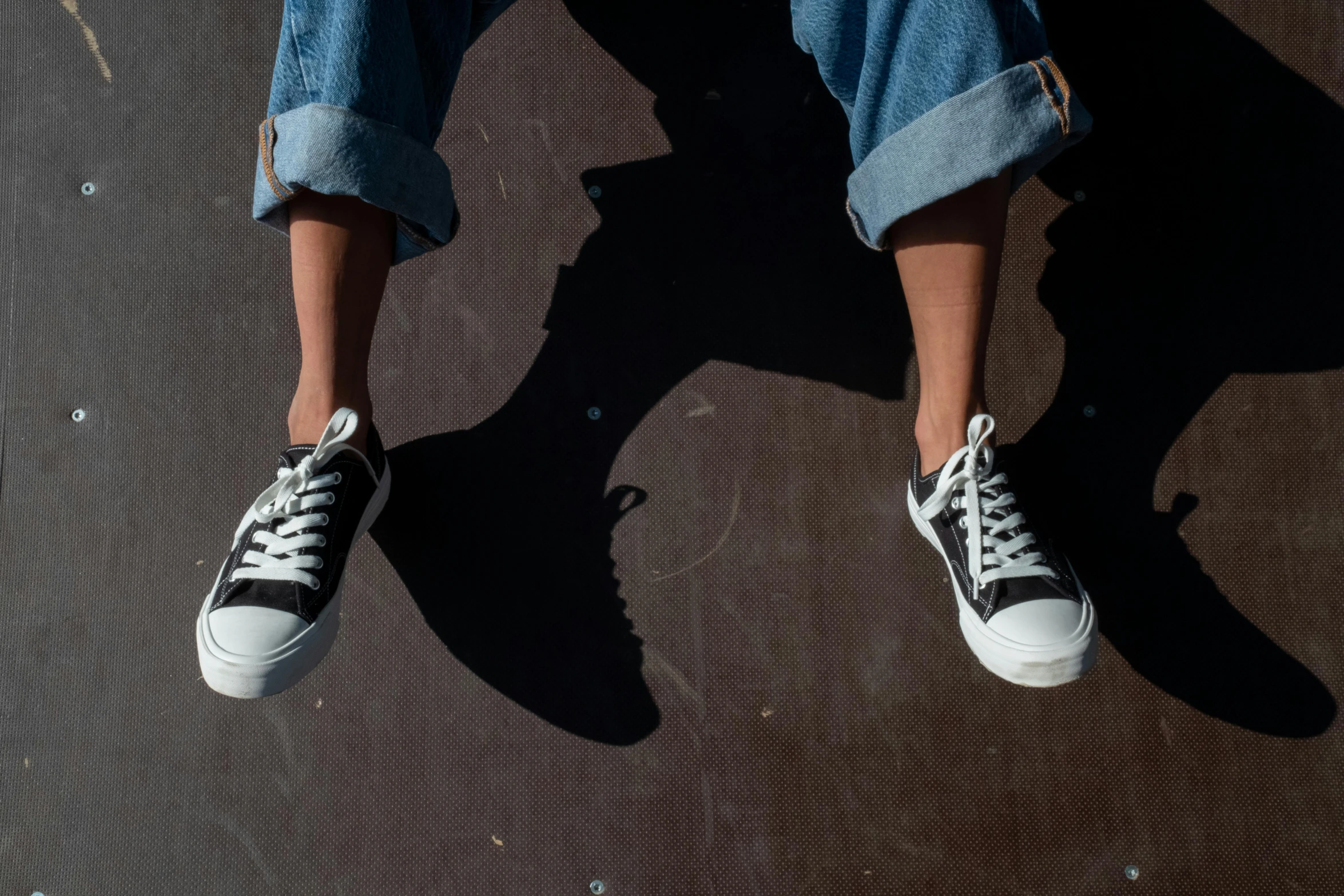 someone is sitting on the skate board wearing shoes