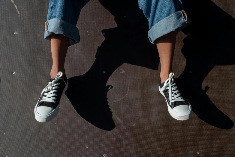 someone is sitting on the skate board wearing shoes