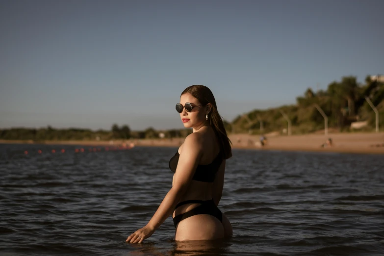woman in black bathing suit standing in water near beach