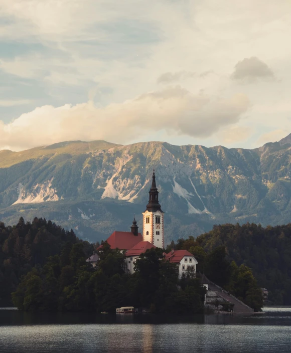 a church steeple rising above the mountains near water