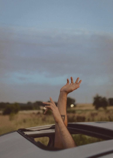 the sun shining through a car windshield as someone raises their hand out
