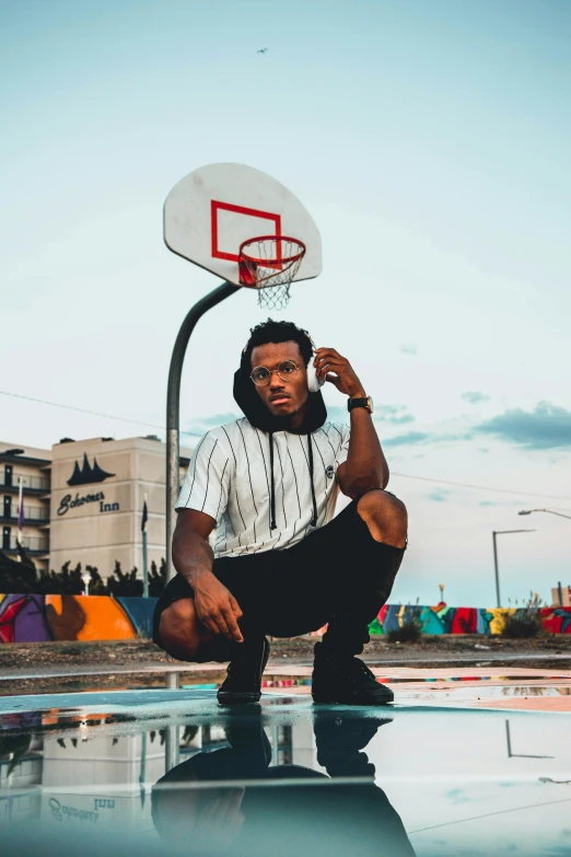 a man sitting next to a basketball net holding a basketball