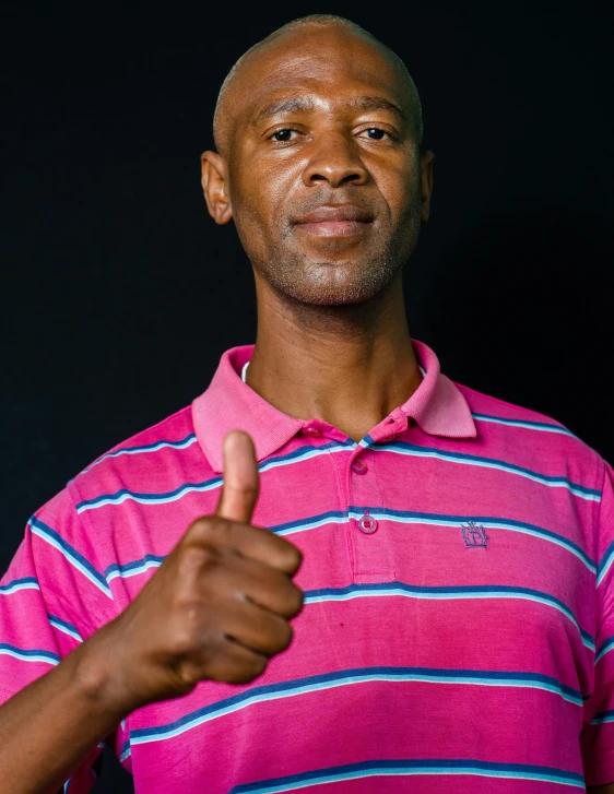 a black man with a pink shirt giving a thumbs up