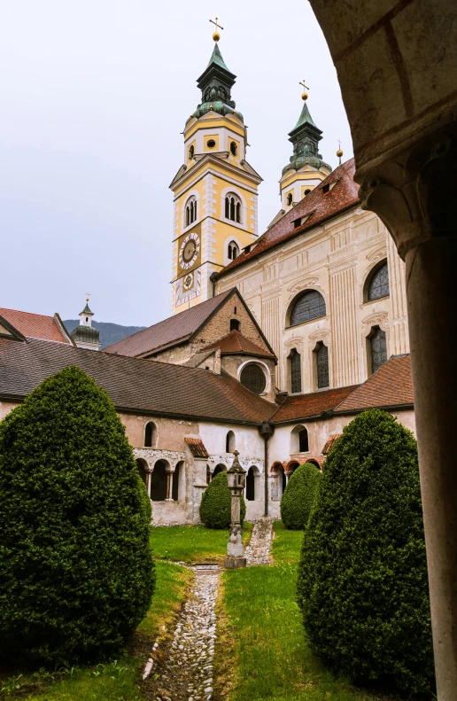 a building has several towers on top and many bushes at the bottom