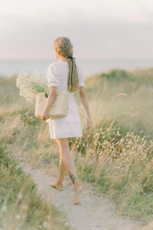 a girl is walking along a path and carrying some flowers