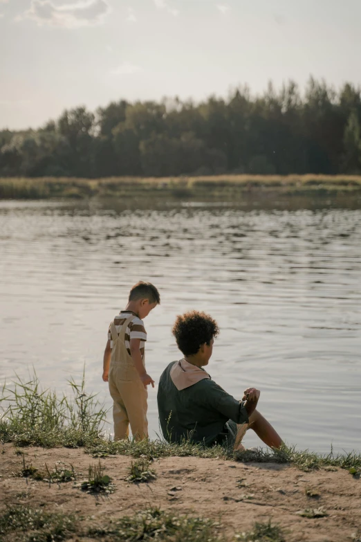 a woman sitting on the beach next to a child