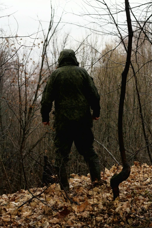 a person in a camouflage jacket walking through leaves