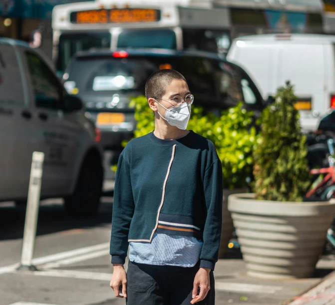 a young man wearing a face mask walking on the street