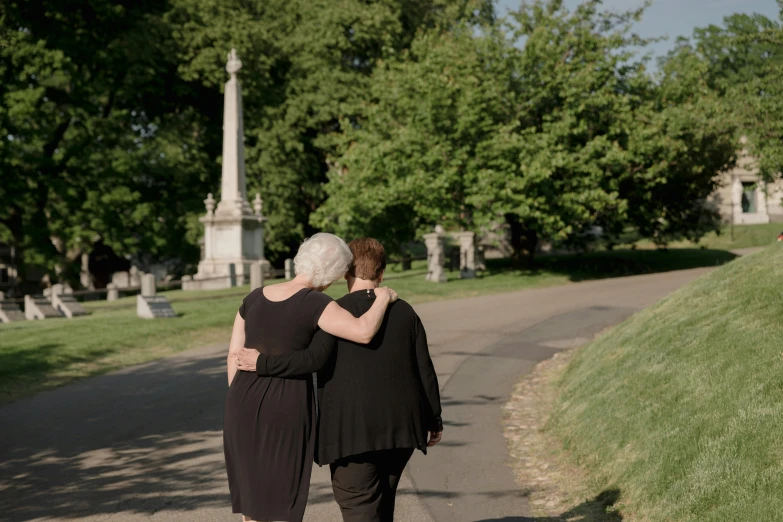 a couple walking down a street next to a park